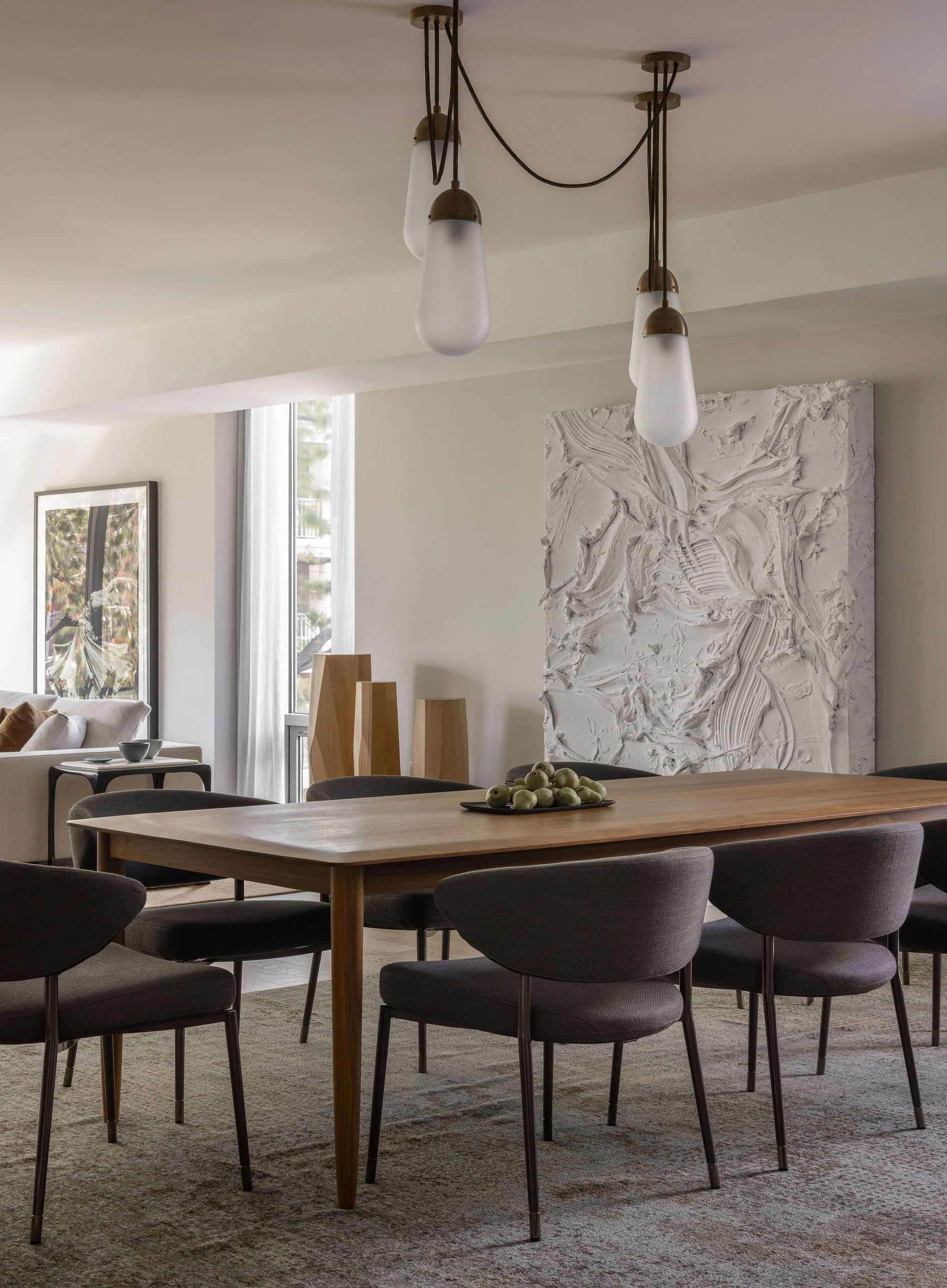 Walnut dining table beneath an Apparatus lariat chandelier in a Georgetown condo, with views to a commissioned Jason Martin painting and a Ruth St. Denis photograph.