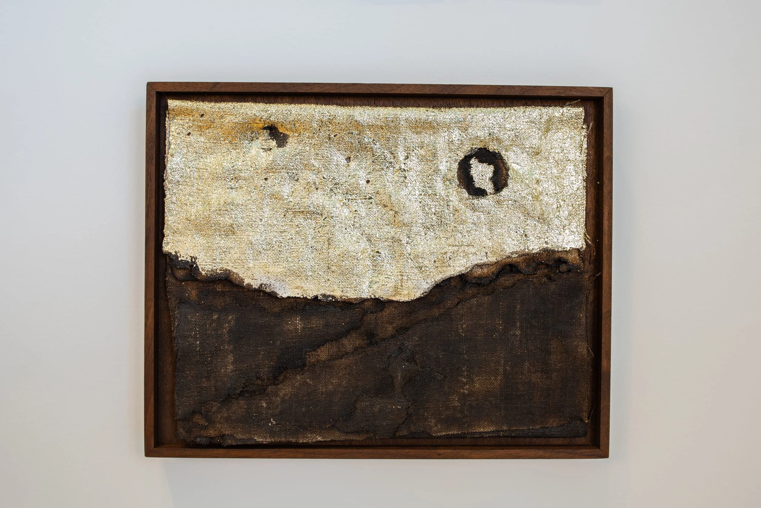 Putting the World Back Together 01 — a small framed charred linen work with gold leaf.