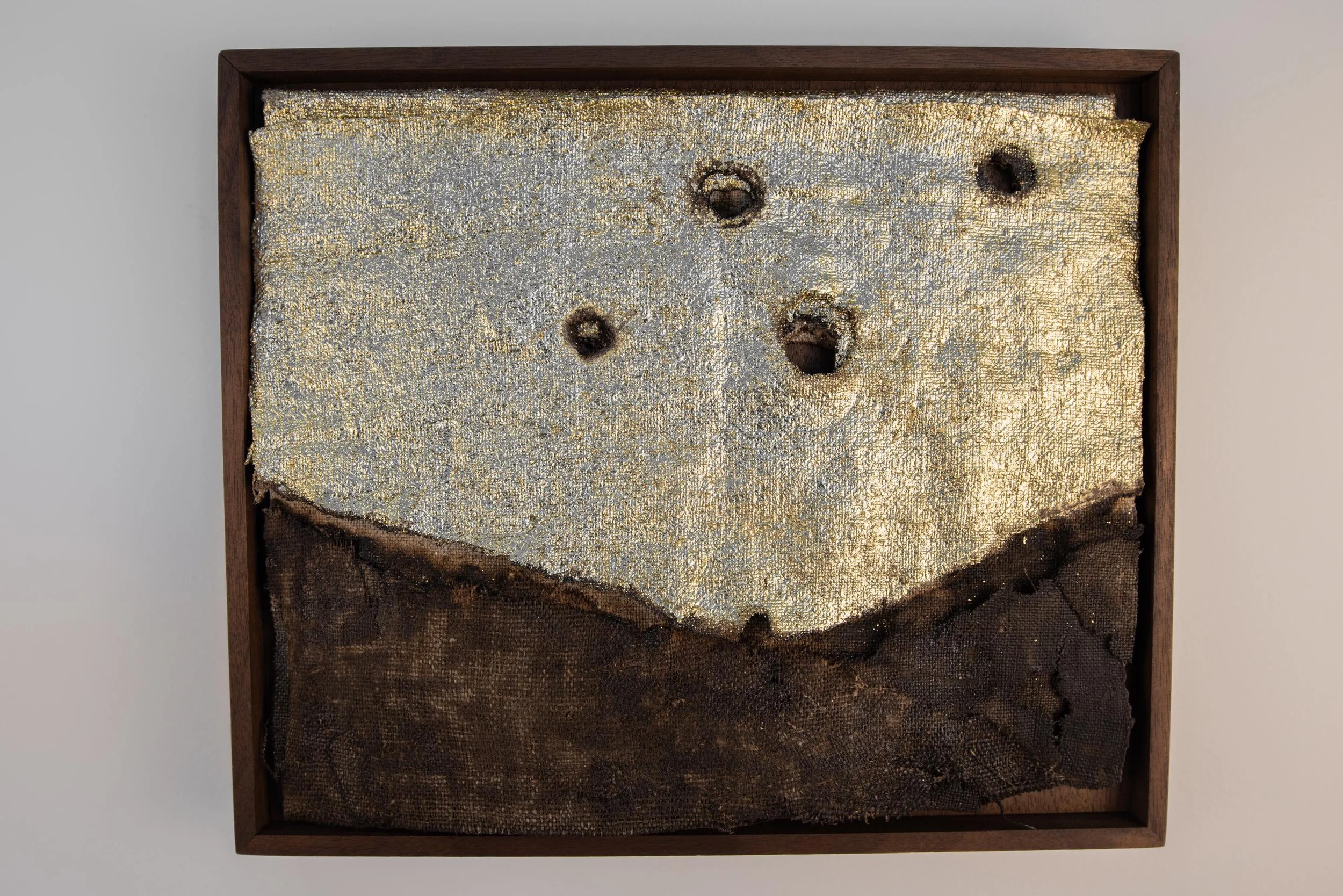 Putting the World Back Together 02 — a small framed charred linen work with gold leaf.