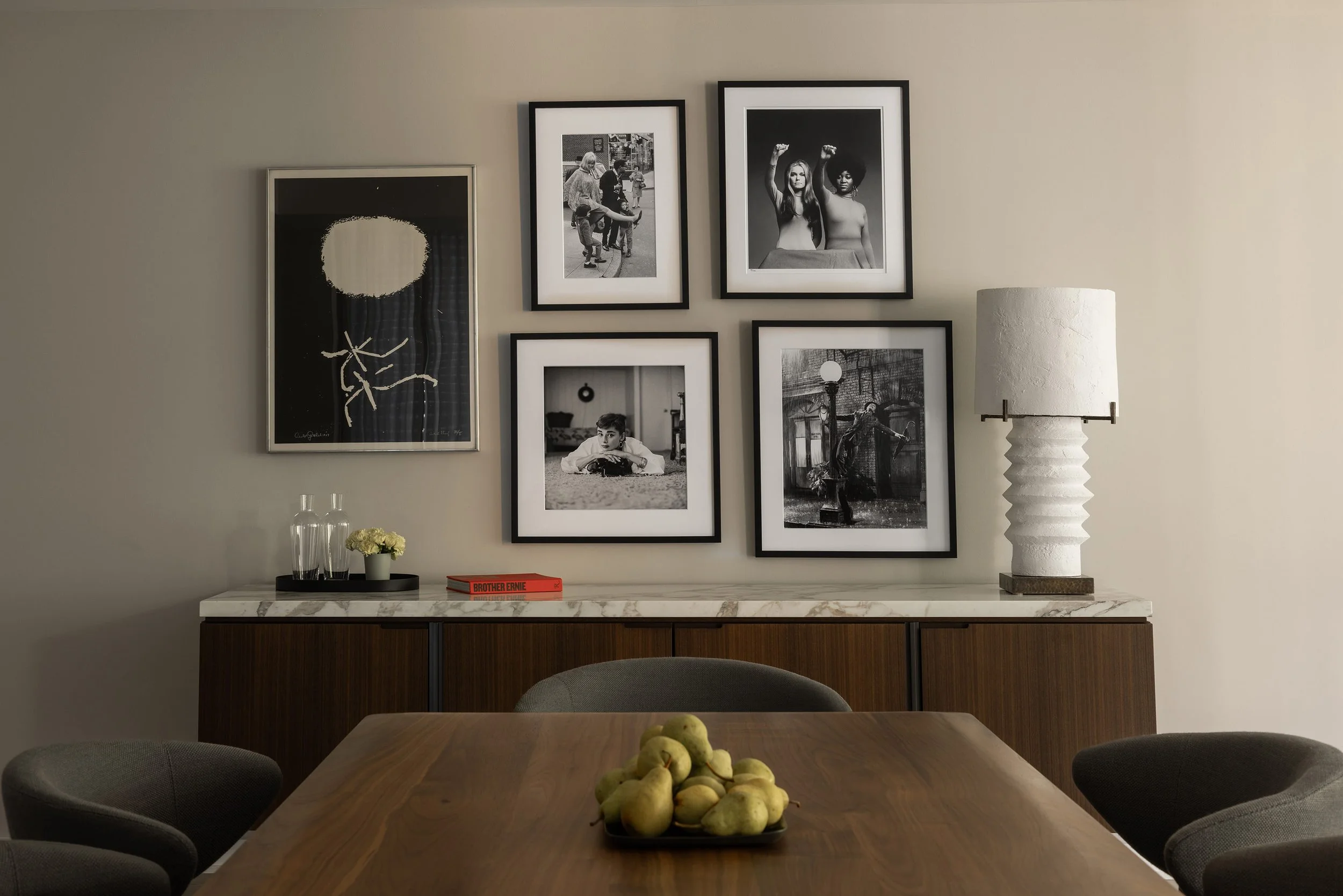 Salon art gallery wall installation in a Georgetown, DC condo, with a plaster lamp from Blackman Cruz, a Gottlieb print, a walnut dining table, and Minotti dining chairs.