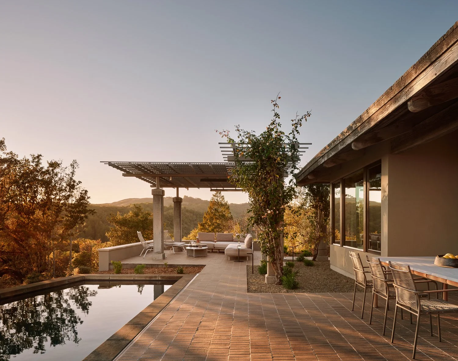 Outdoor living featuring expansive wine country views, architectural trellis shading, and layered landscape design, with Sutherland outdoor dining and Roda lounge seating.
