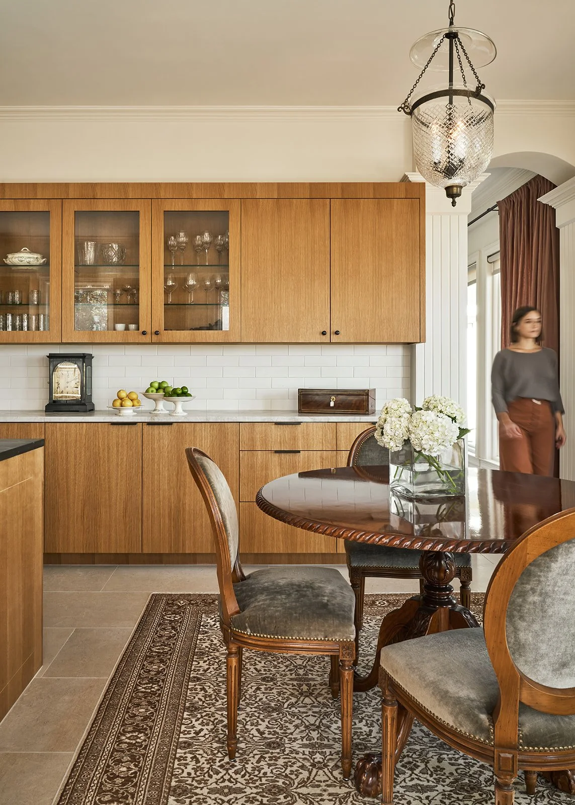 Remodeled Austin kitchen featuring custom inset white oak cabinetry, Taj Mahal quartzite countertops, Ann Sacks tile backsplash, Leuders limestone floors, and a vintage round dining table with chairs.