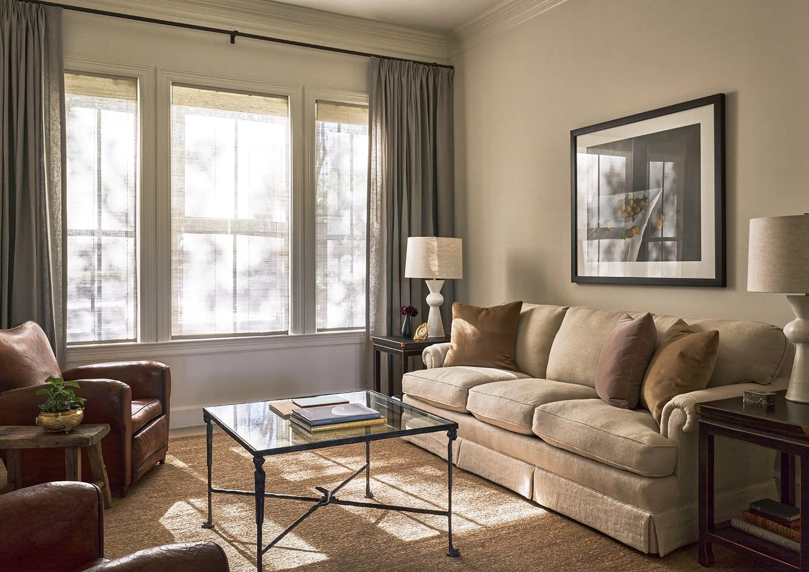 Front sitting room featuring a reupholstered sofa in Design of the Times linen, Kate Breakey lemon photograph, Paris flea market club chairs, and a bronze coffee table with Caryatids by H. Cordero and Molyneux.