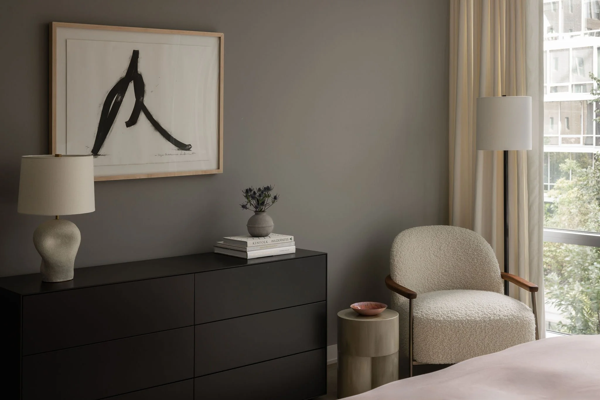 Guest bedroom in a Georgetown condo, featuring a modern black dresser, sculptural ceramic table lamp, and a framed Bernar Venet print styled with soft neutral furnishings.