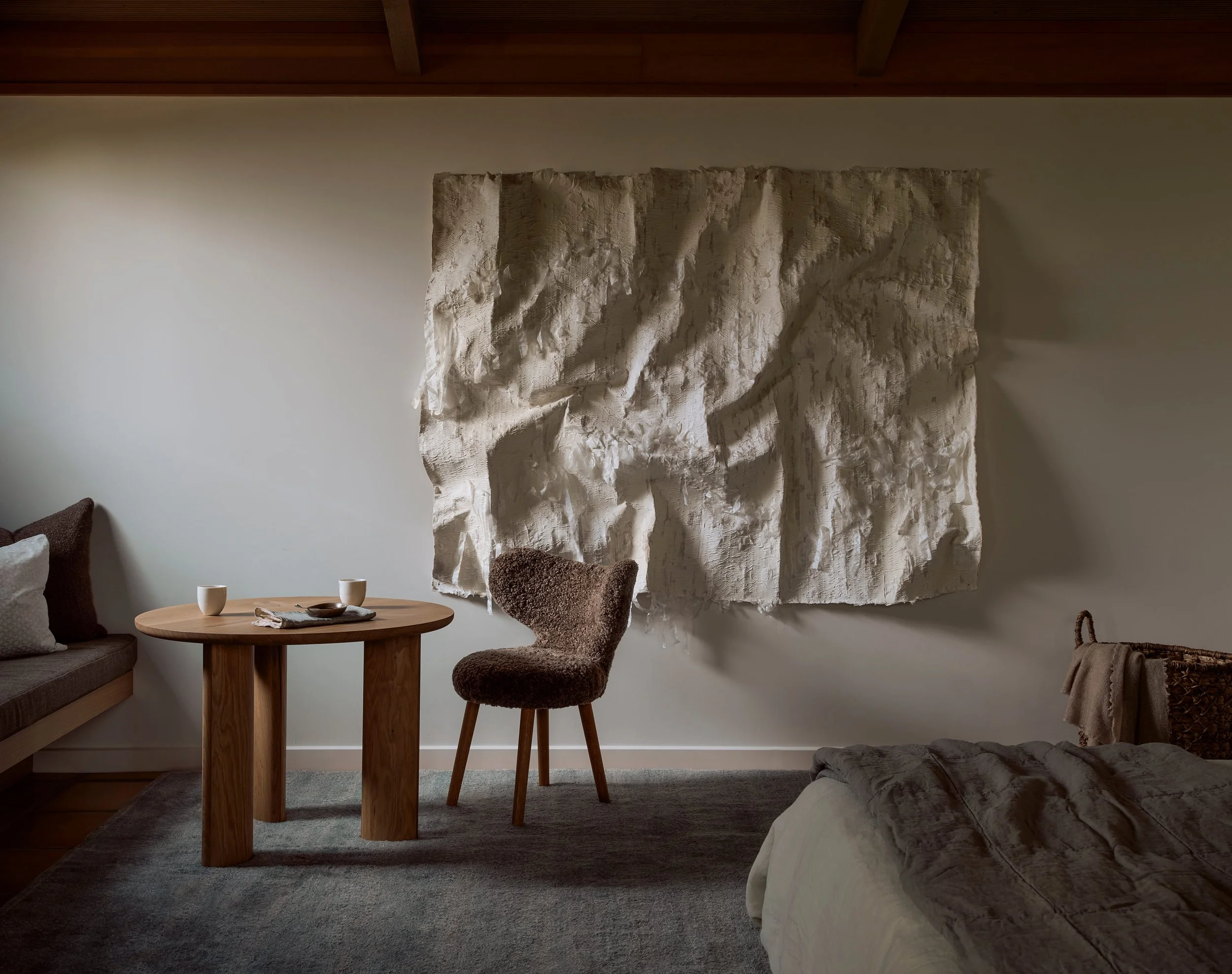 A Kenny Nguyen tapestry anchors a Sonoma primary bedroom with custom furniture and a lambskin chair.
