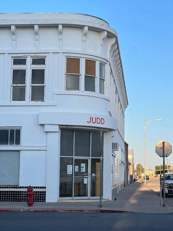A white corner building against a blue Marfa sky